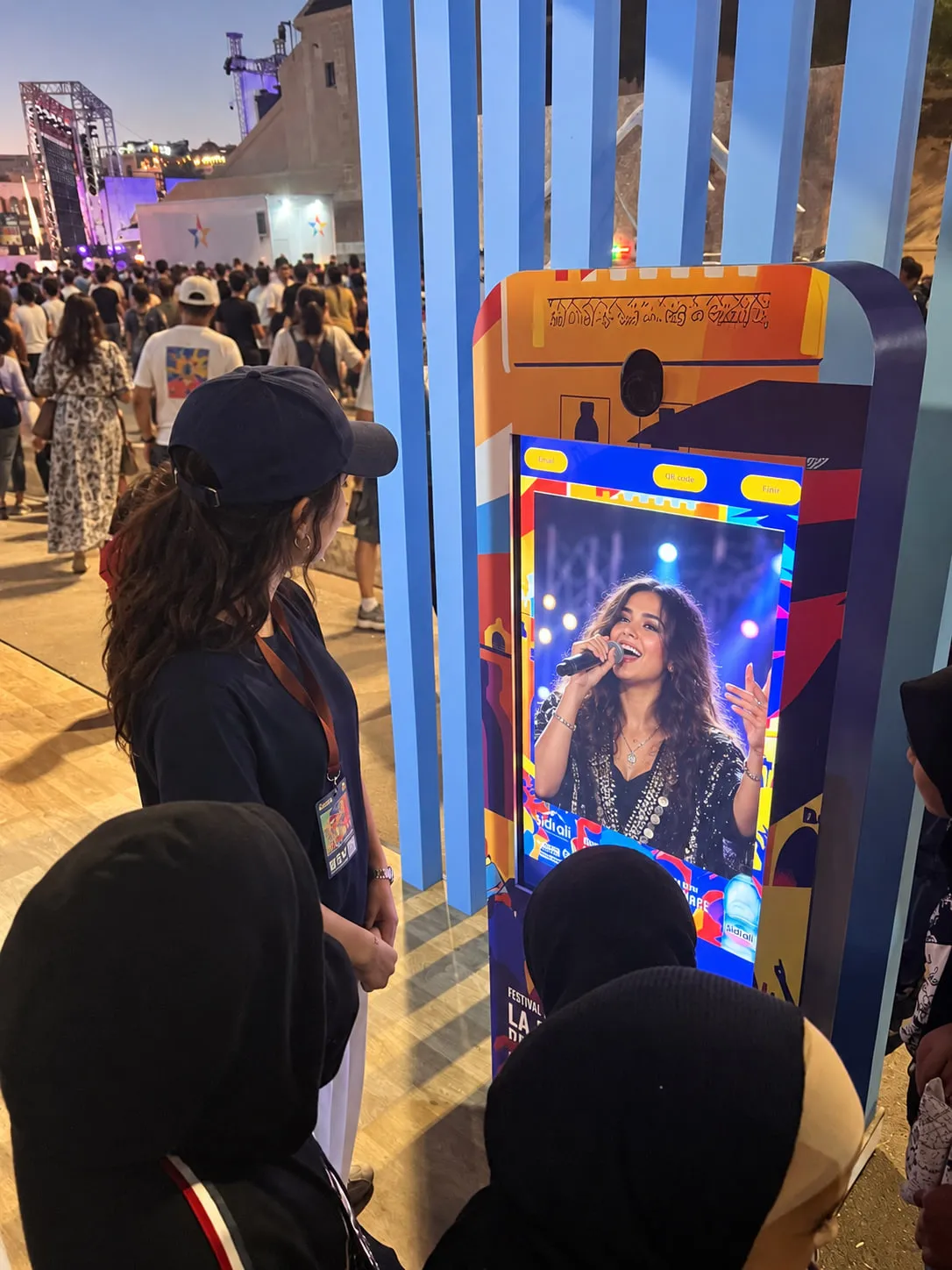 L’écran de la borne Sidi Ali affiche un festivalier transformé en chanteuse sur scène, micro en main