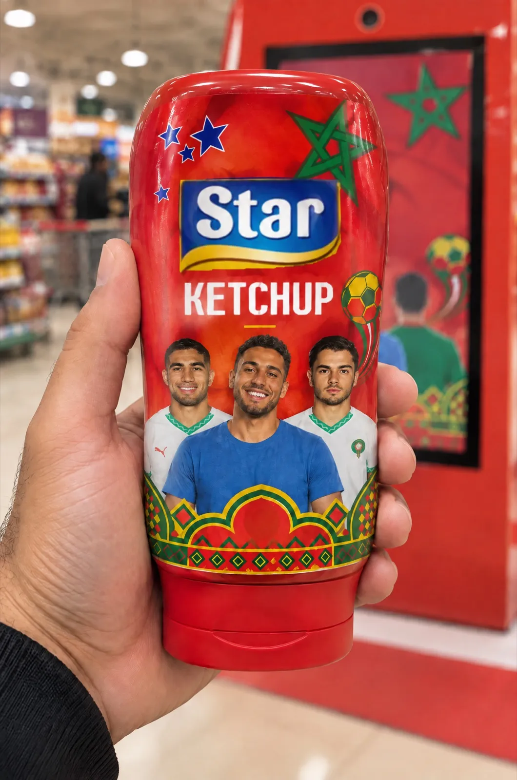Une main présente une bouteille de ketchup Star dont l’étiquette place le portrait du client au centre, entre les joueurs