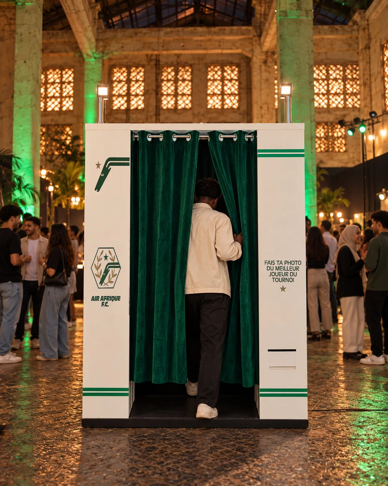 La cabine Air Afrique × Nike vue de face dans la halle, un visiteur entre derrière le rideau vert