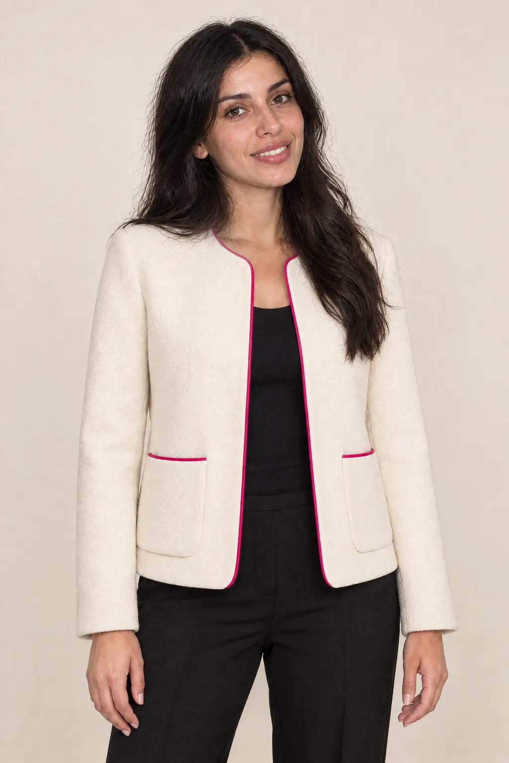 The woman wears the ivory jacket with pink trim