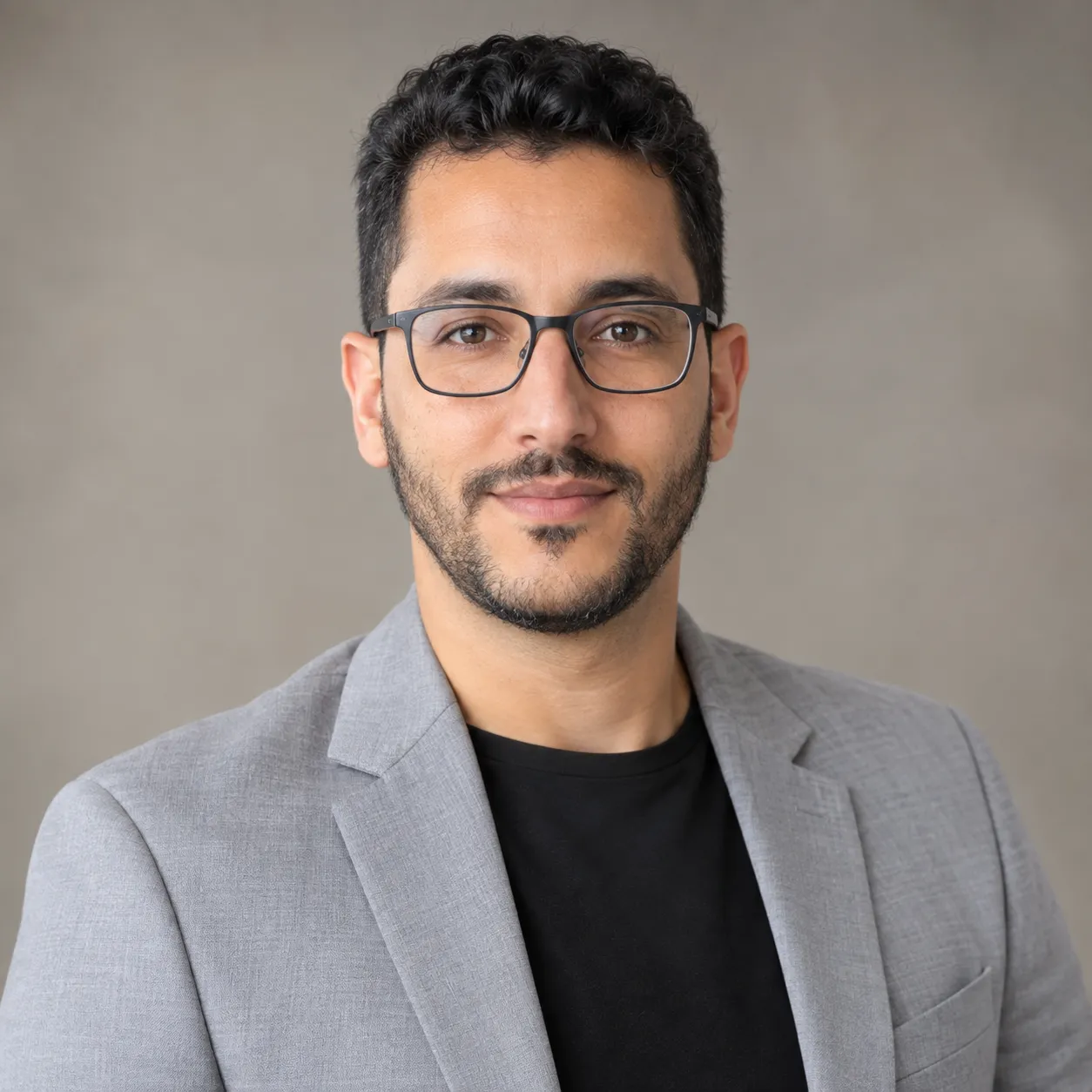 Portrait d’un homme à lunettes en veste grise, sur fond neutre
