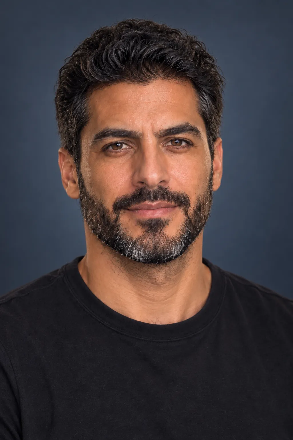 A professional headshot of the man against a blue-grey background