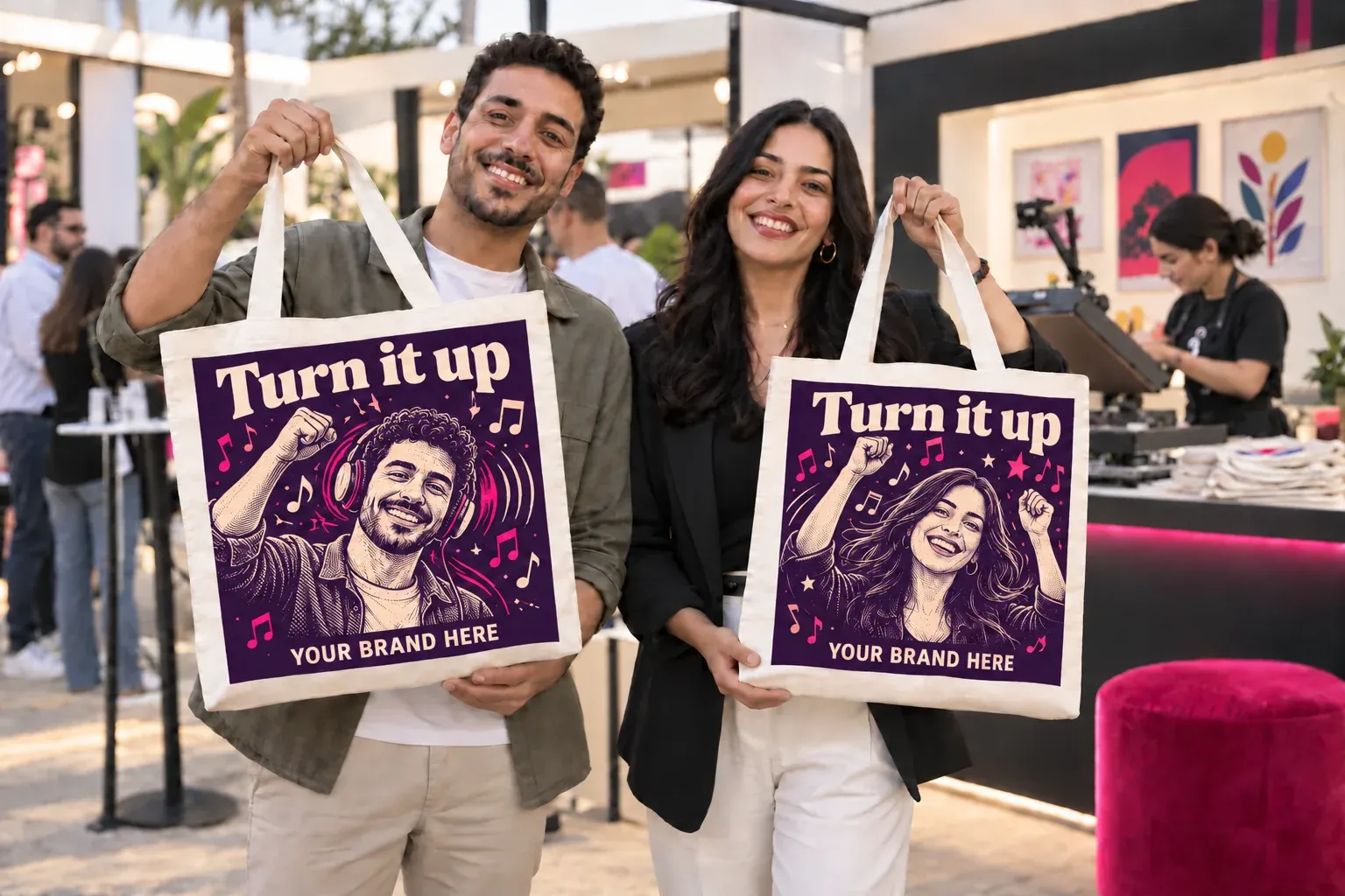 Two guests hold up tote bags printed with a campaign poster starring each of them at a Live Print workshop