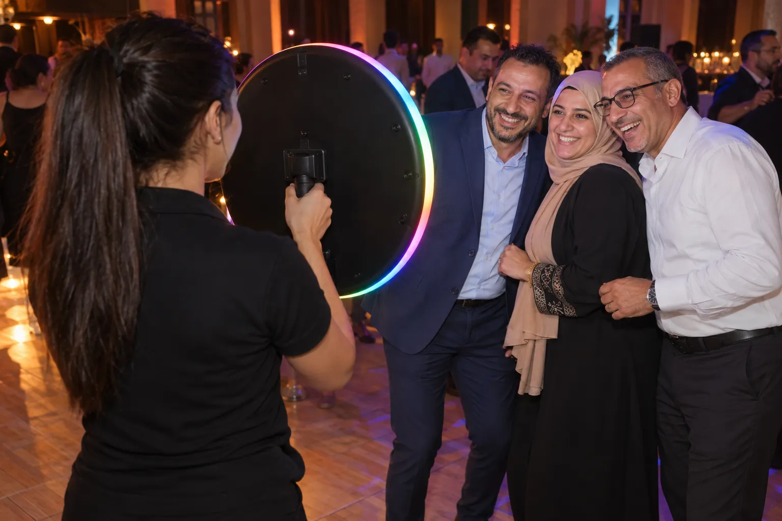 Sur la piste d’une soirée d’entreprise, trois collègues posent face à l’anneau lumineux aux couleurs vives que leur tend l’animatrice
