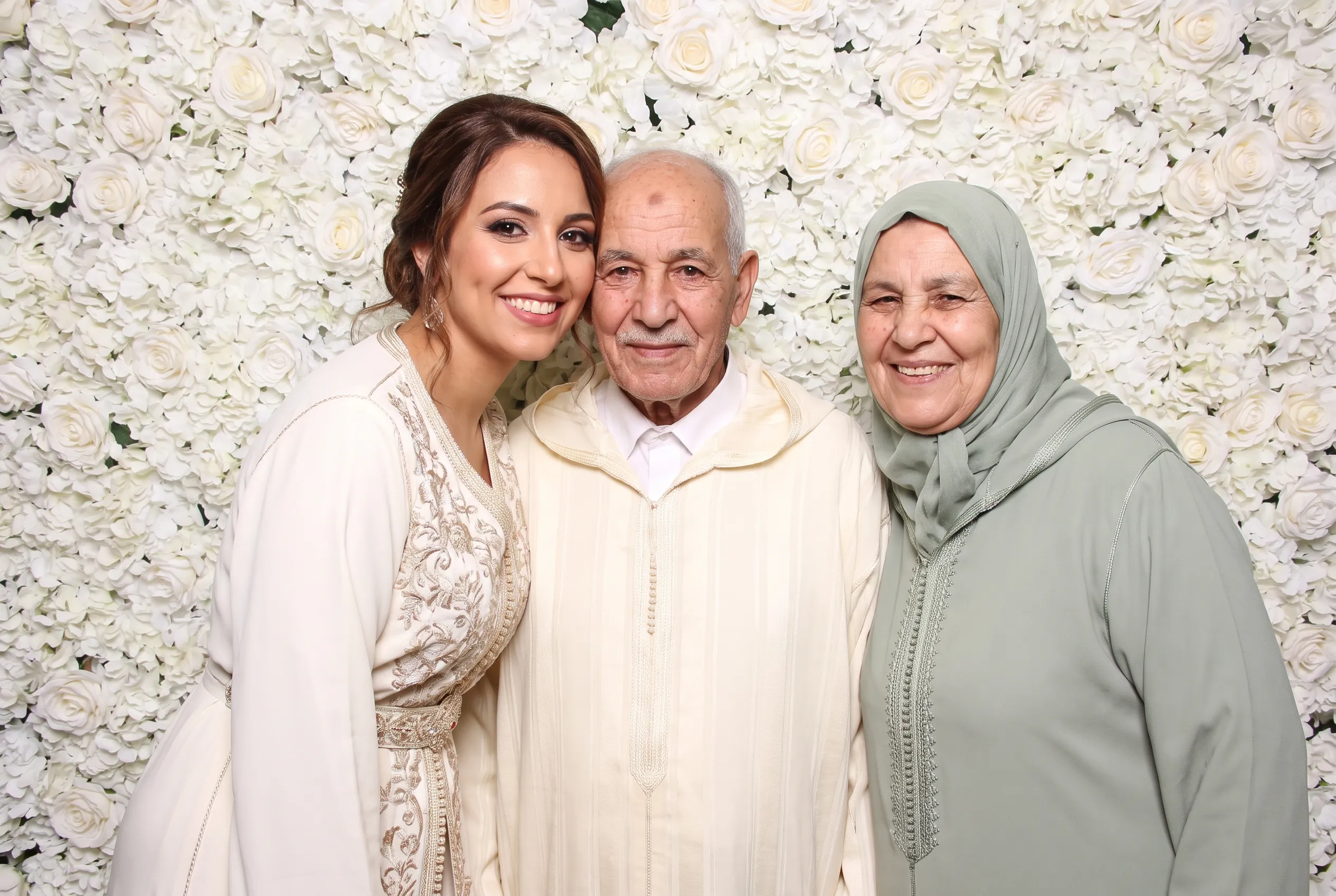 Portrait d’une mariée et de ses grands-parents devant des fleurs.