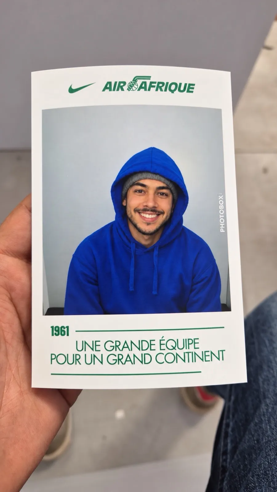 Une main tient un tirage photo Air Afrique × Nike : portrait souriant au cadre vert de la campagne Air Afrique